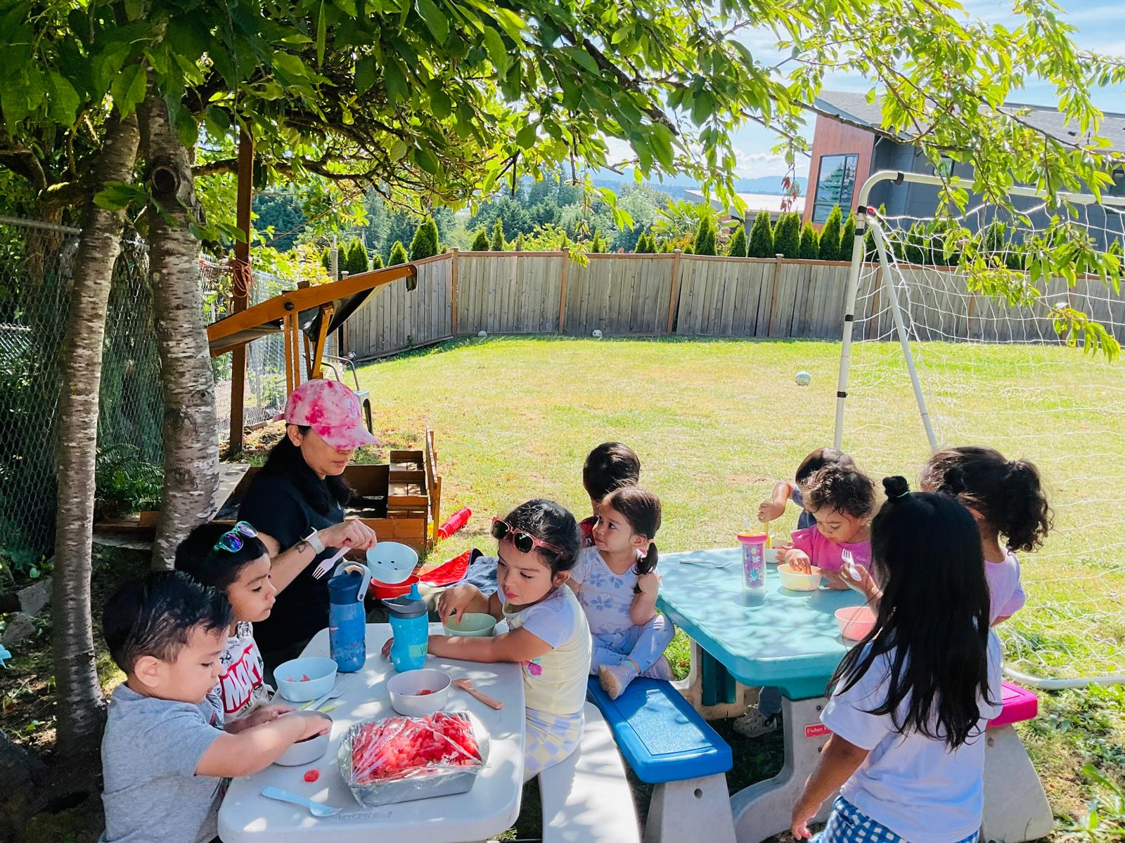 Children enjoying an outdoor water play table in the backyard