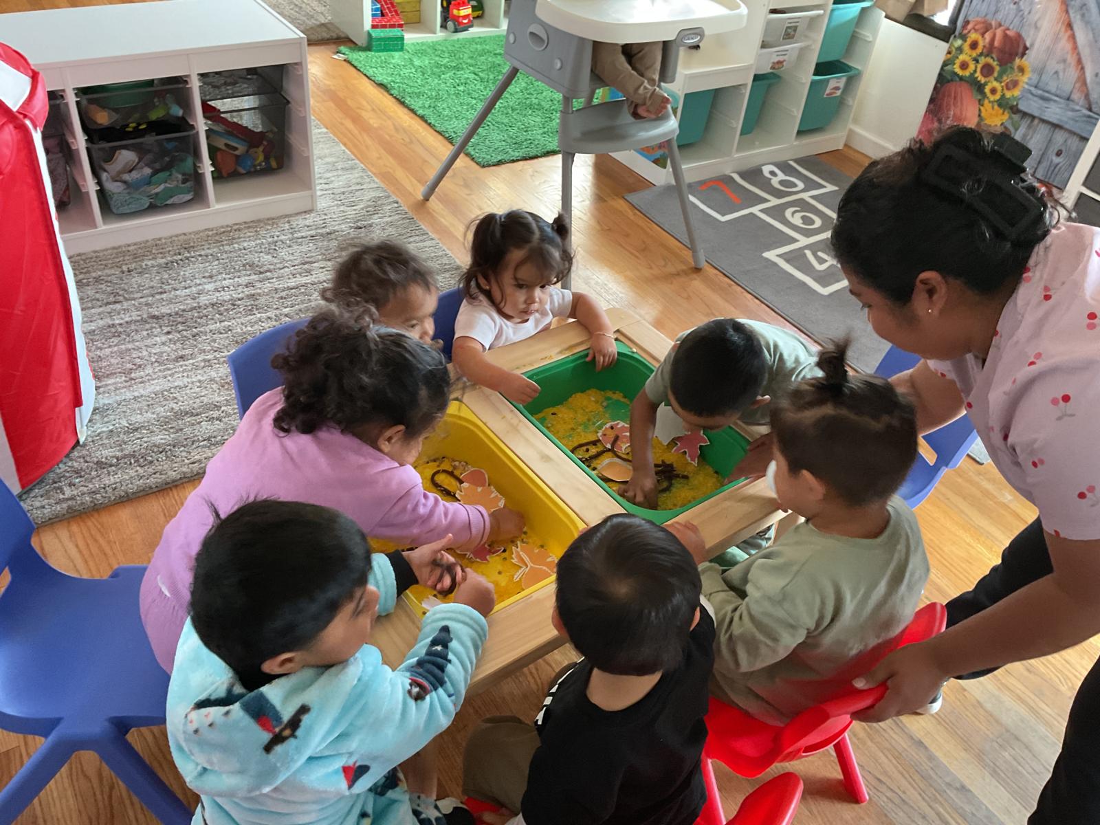 Children exploring a sensory table together with their teacher